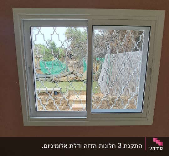 חלון הזזה מאלומיניום לבן עם סורג מעוצב מותקן בבית